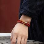  Close-up of cinnabar evil ward bracelet on wrist with gold gourd pendant catching light