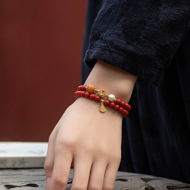  Close-up of cinnabar evil ward bracelet on wrist with gold gourd pendant catching light