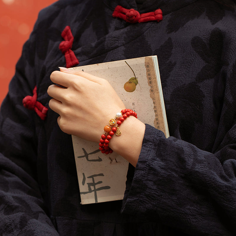 Woman reading with a cinnabar fortune bracelet on her wrist — everyday protection and good luck jewelry
