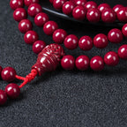 Close-up of sculpted purple cinnabar guru bead on 108-bead meditation mala.