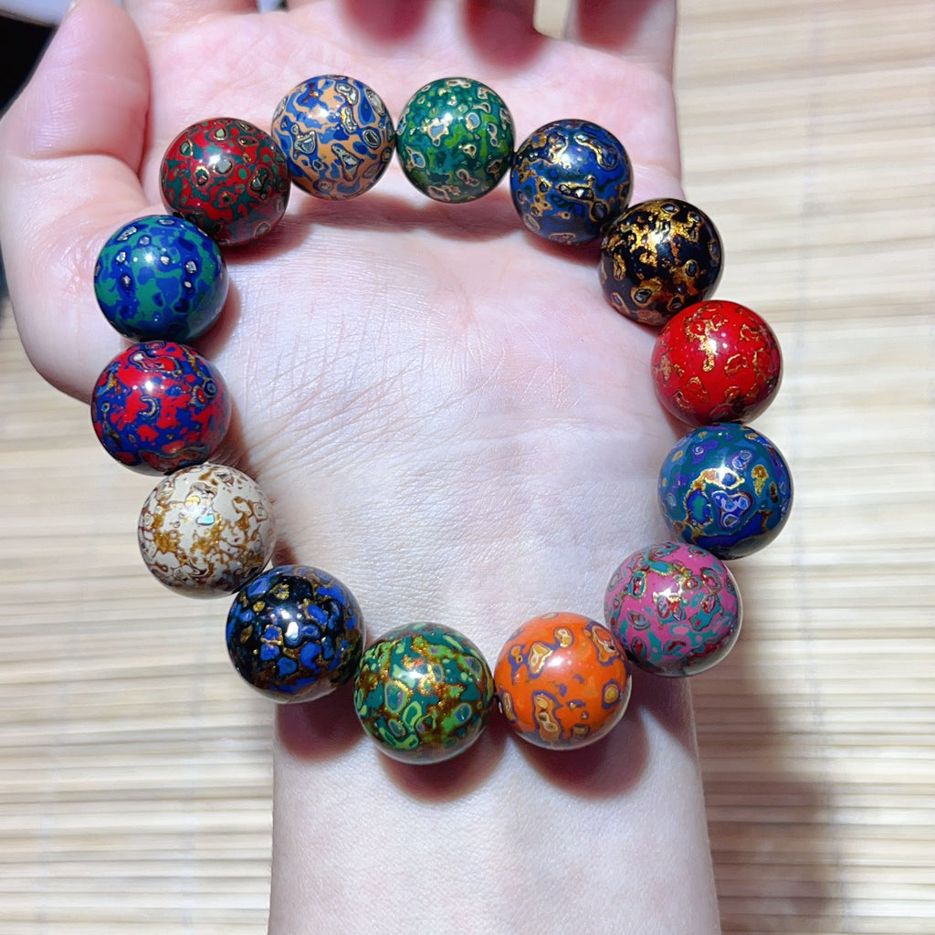 Colorful handmade lacquer bracelet 10mm beads held in palm full circle display showing unique multicolor artisan patterns Taoist KaiGuang wealth protection unisex spiritual bracelet