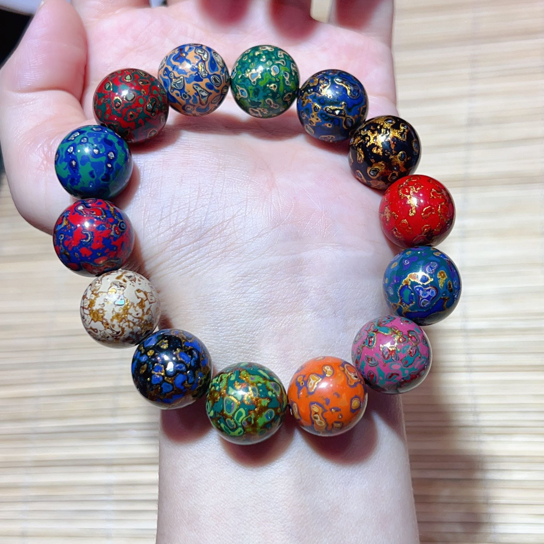 Colorful handmade lacquer bracelet 10mm beads held in palm full circle display showing unique multicolor artisan patterns Taoist KaiGuang wealth protection unisex spiritual bracelet