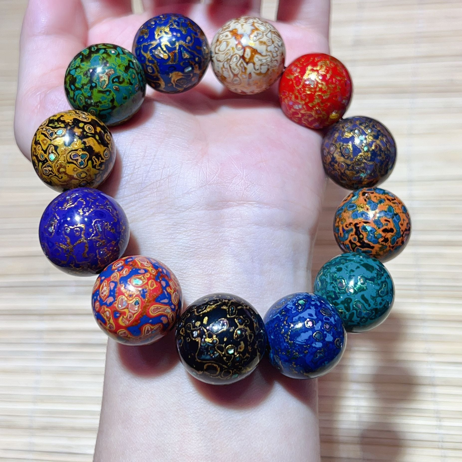 Colorful handmade lacquer bracelet 15mm beads held in palm showing unique multicolor lacquer patterns Taoist KaiGuang wealth protection artisan spiritual jewelry