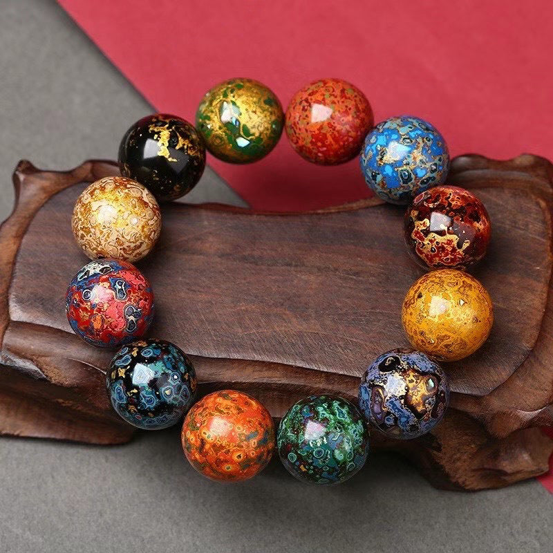 Colorful handmade lacquer bead bracelet large beads displayed on wood prop showing multicolor patterns red gold blue green Taoist KaiGuang wealth attraction protection