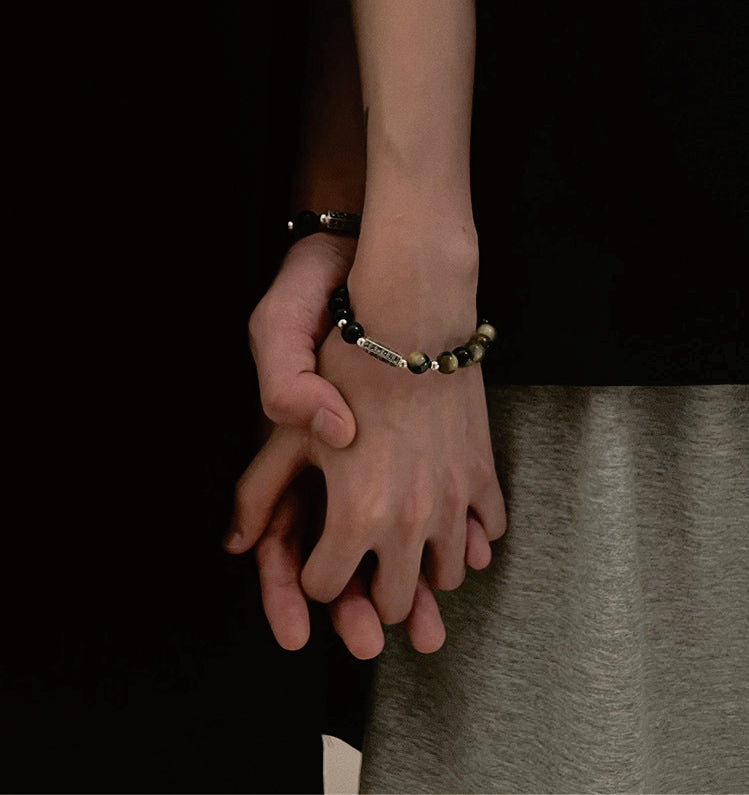 Couple holding hands wearing Taoist Kaiguang love protection bracelets symbolizing emotional connection and relationship bonding