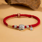 Red braided cord bracelet with silver lion head charm and rune beads on warm stone background showing Taoist KaiGuang love protection couple jewelry detail