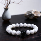 Close-up of female feng shui bracelet with white turquoise beads and obsidian center, representing yin energy balance