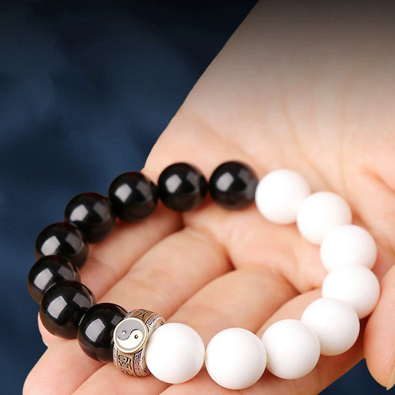 feng shui yin yang bracelet held in hand showing bead size texture and natural obsidian and white turquoise material