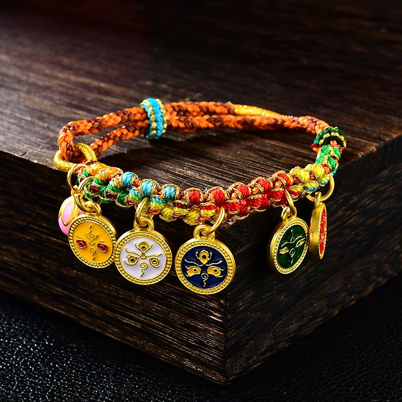 Five Gods of Wealth Taoist KaiGuang bracelet five-color braided rope gold enamel medallions on dark wood surface