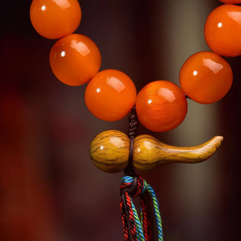 A close-up shot of a hand-carved wood hulu charm on a Taoist bracelet, a traditional money magnet for attracting fortune and good luck.
