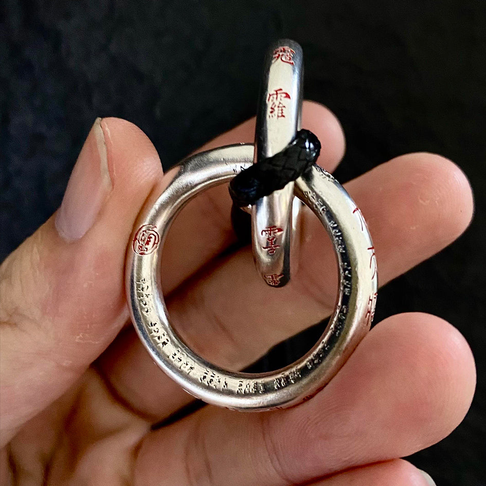 A close-up shot of the silver Qiankun Circle being held, demonstrating its substantial quality as a high-end protective talisman.