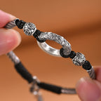 Close-up hand holding jade peace buckle bracelet showing carved silver dragon cloud pattern peace buckle ring black yin yang beads engraved silver spacers with Chinese characters silver twisted rope Taoist KaiGuang protection evil warding detail