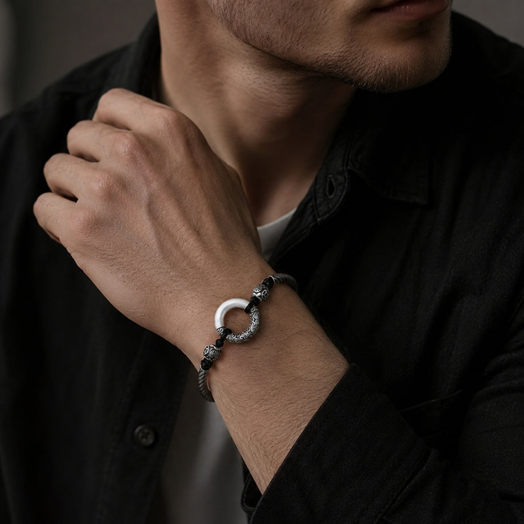 Man in black shirt wearing jade peace buckle protection bracelet on wrist silver twisted rope black yin yang beads carved silver spacers ping an charm Taoist KaiGuang evil warding protection amulet dark background