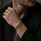 Man in black shirt wearing jade peace buckle protection bracelet on wrist silver twisted rope black yin yang beads carved silver spacers ping an charm Taoist KaiGuang evil warding protection amulet dark background