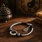 Jade peace buckle protection bracelet overhead view silver twisted rope black yin yang beads carved silver spacers ping an charm on wooden table bronze incense burner yin yang bagua ancient books Taoist KaiGuang consecrated evil warding
