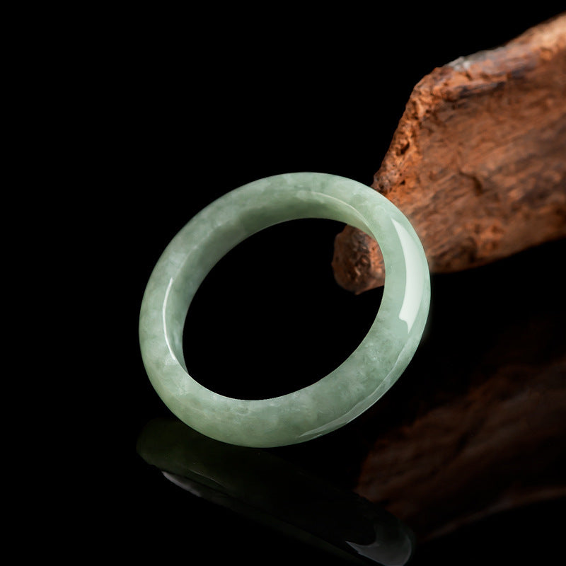  Natural jadeite wealth attraction ring leaning on dark wood low angle black background showing translucent green clarity