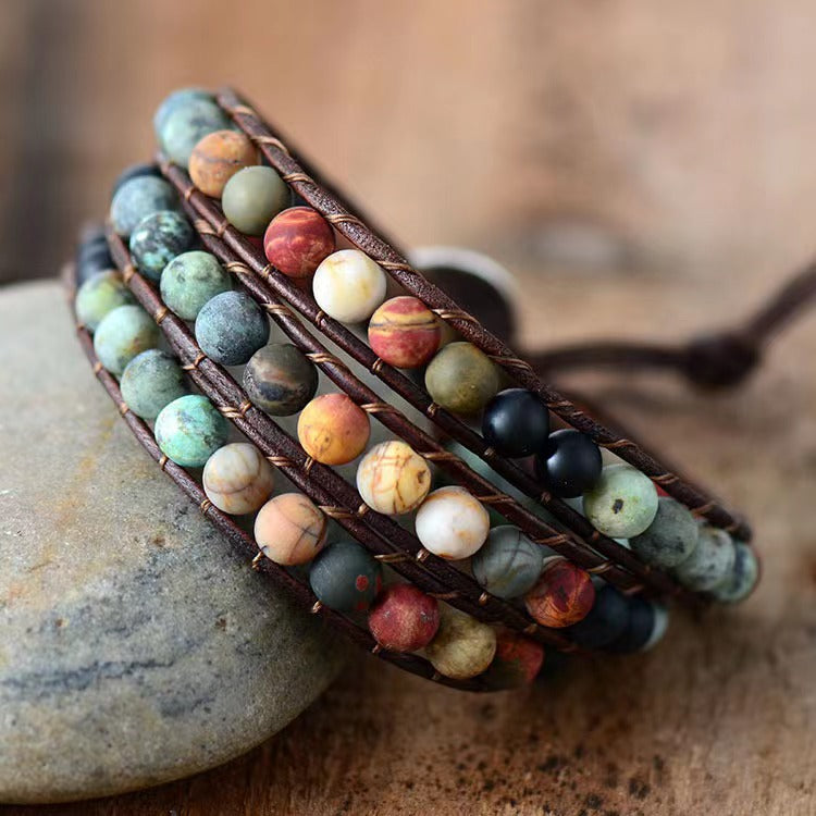 Matte blue green gemstone triple wrap love protection bracelet on wooden surface
