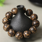 Men's luxury tiger stripe agarwood bracelet 18mm large beads on black vase prop showing gold brown tiger stripe patterns Taoist KaiGuang wealth meditation stress relief