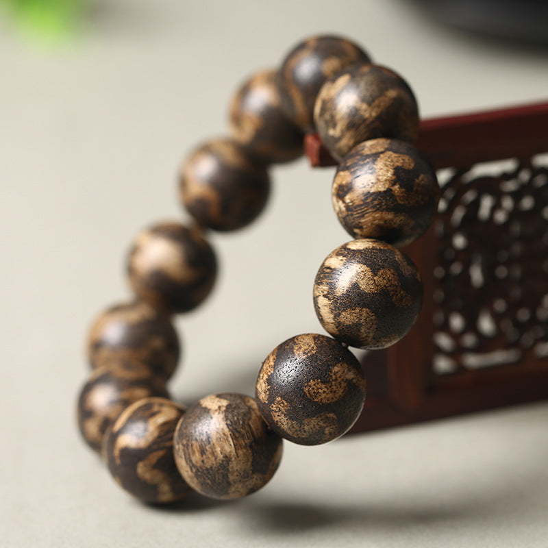 Men's luxury tiger stripe agarwood bracelet 18mm beads on redwood carved prop showing deep brown gold tiger stripe texture Taoist KaiGuang wealth meditation spiritual bracelet