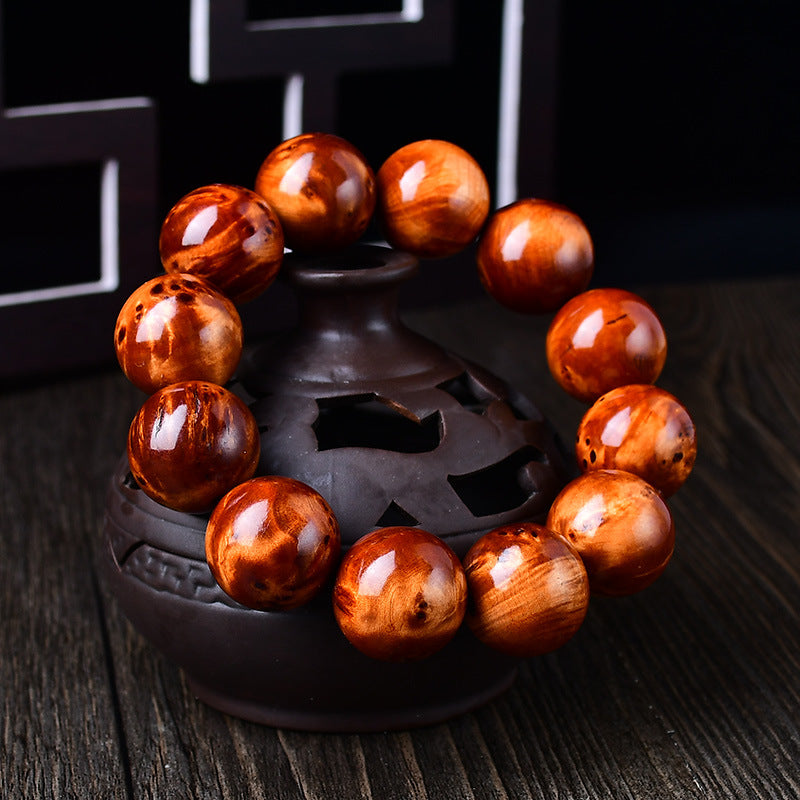Men's stress relief cliff cypress bracelet 18mm large beads displayed on dark incense burner showing orange red wood grain Taoist KaiGuang grounding energy evil ward protection