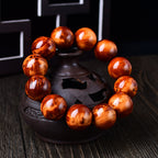 Men's stress relief cliff cypress bracelet 18mm large beads displayed on dark incense burner showing orange red wood grain Taoist KaiGuang grounding energy evil ward protection
