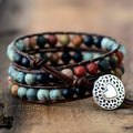 Mixed matte gemstone triple wrap bracelet with multicolor natural stone beads on rock surface