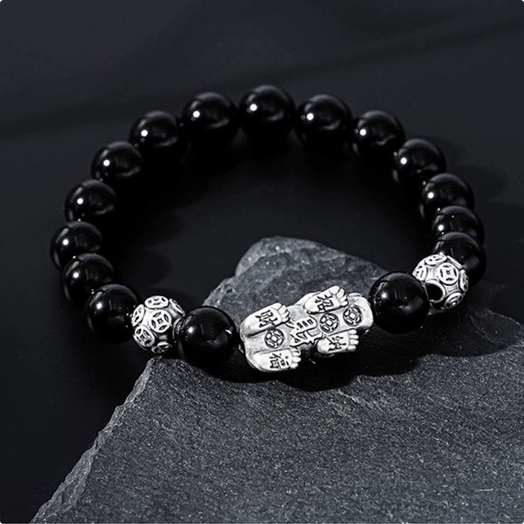 Black obsidian Pixiu money bracelet with silver guardian fortune beads on black white diagonal background wealth bracelet
