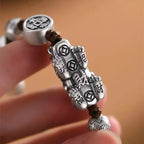 Close-up detail of Pixiu charm showing engraved text “Attract Wealth and Prosperity” at the base with clear texture and carving detail.