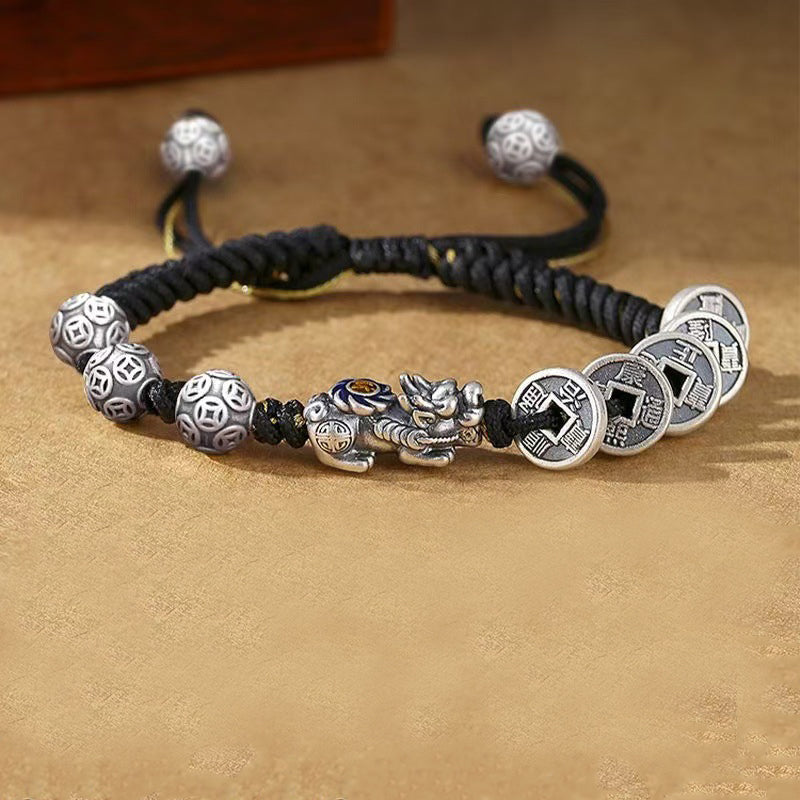 Pixiu five coin Taoist KaiGuang wealth bracelet side view showing silver coin pattern beads and ancient coin charms on warm leather background