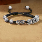 Pixiu five coin Taoist KaiGuang wealth bracelet side view showing silver coin pattern beads and ancient coin charms on warm leather background