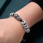  Pixiu five coin wealth bracelet worn on wrist against black sleeve showing silver ancient coin charms and blue enamel Pixiu Taoist KaiGuang jewelry
