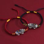  Red and black cord Pi Xiu bracelets side by side on red background showing silver wealth guardian charm
