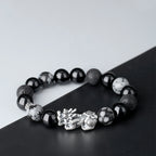 Pixiu obsidian KaiGuang fortune bracelet on black and white diagonal background showing silver Pixiu charm and bead contrast