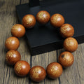 Professional Taoist ritual artifact: A bracelet of gold-painted thunderstruck wood beads featuring the Five Thunders Talisman and Tai Chi Bagua symbols, arranged in a ring on a dark wooden surface for active energy clearing and protection.