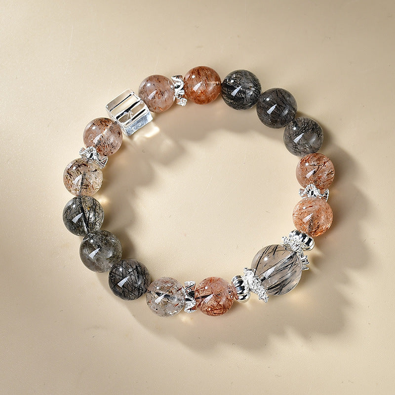 Overhead view black rutilated quartz strawberry quartz protection grounding bracelet arranged in circle cream background silver spacers KaiGuang Taoist consecrated