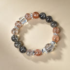 Overhead view black rutilated quartz strawberry quartz protection grounding bracelet arranged in circle cream background silver spacers KaiGuang Taoist consecrated