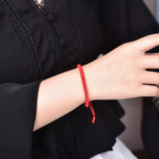 woman wearing red rope vajra knot bracelet wrist taoist kaiguang evil ward protection dark background elegant