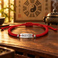 Red string Taoist luck talisman bracelet with S925 silver charm on a wooden altar table, Bagua and incense burner behind