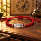 Red string Taoist luck talisman bracelet with S925 silver charm on a wooden altar table, Bagua and incense burner behind