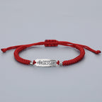 Red string bracelet with engraved Zhuan Yun Fu silver luck talisman, white background