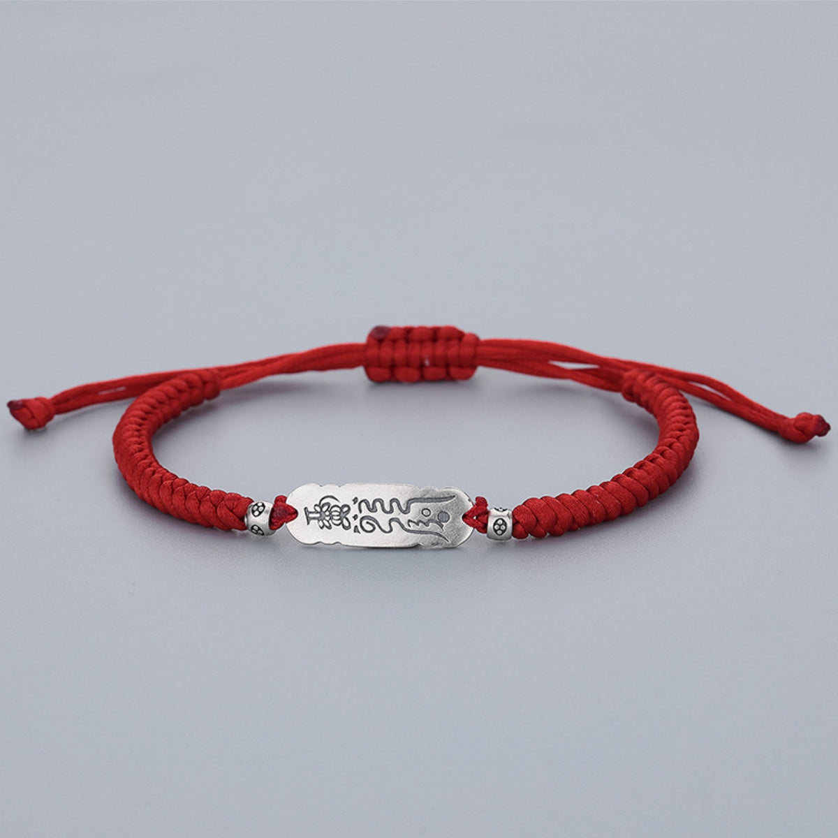Red string bracelet with engraved Zhuan Yun Fu silver luck talisman, white background