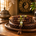 Rosewood 108 bead meditation mala four wrap bracelet with turquoise green jade and bodhi seed accents on carved wooden tray beside bronze incense burner yin yang bagua background Taoist KaiGuang grounding