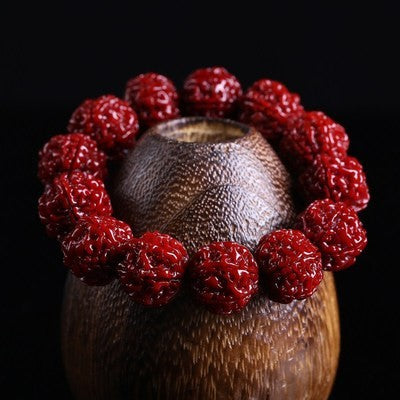 Deep red Nepal Rudraksha protection bracelet displayed on natural coconut shell showing full bead texture and rich patina