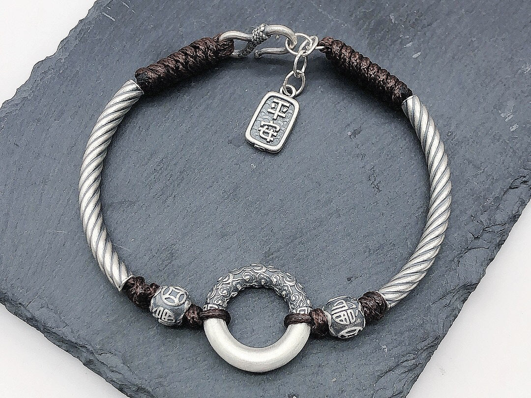 Silver twisted rope peace buckle protection bracelet on dark slate white jade peace buckle ring carved silver cloud beads ping an charm pendant adjustable clasp Taoist KaiGuang evil warding consecrated amulet