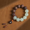 Tai chi yin yang meditation bracelet white quartz and carved tea wood beads overhead view on warm leather background Taoist KaiGuang talisman