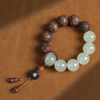 Tai chi yin yang meditation bracelet white quartz and carved tea wood beads overhead view on warm leather background Taoist KaiGuang talisman