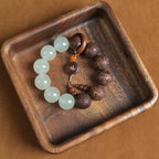 Tai chi yin yang meditation talisman bracelet with white quartz tea wood beads and Fu copper pendant in wooden bowl overhead shot