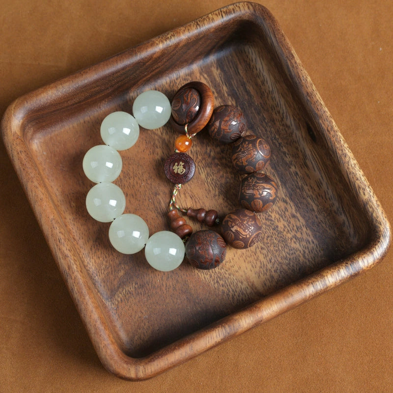 Tai chi yin yang meditation talisman bracelet with white quartz tea wood beads and Fu copper pendant in wooden bowl overhead shot