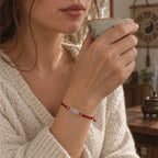 Woman sipping tea in a sunlit tea room, wearing the Taoist good luck bracelet on her wrist