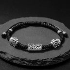 Taoist KaiGuang dual Pixiu sterling lock bracelet black braided cord full view on dark rock wealth guardian protection jewelry